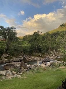 A tranquil river flowing past ancient temples nestled in green hills at sunset.