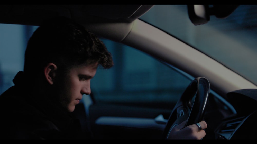 a man sitting in a car holding a steering wheel