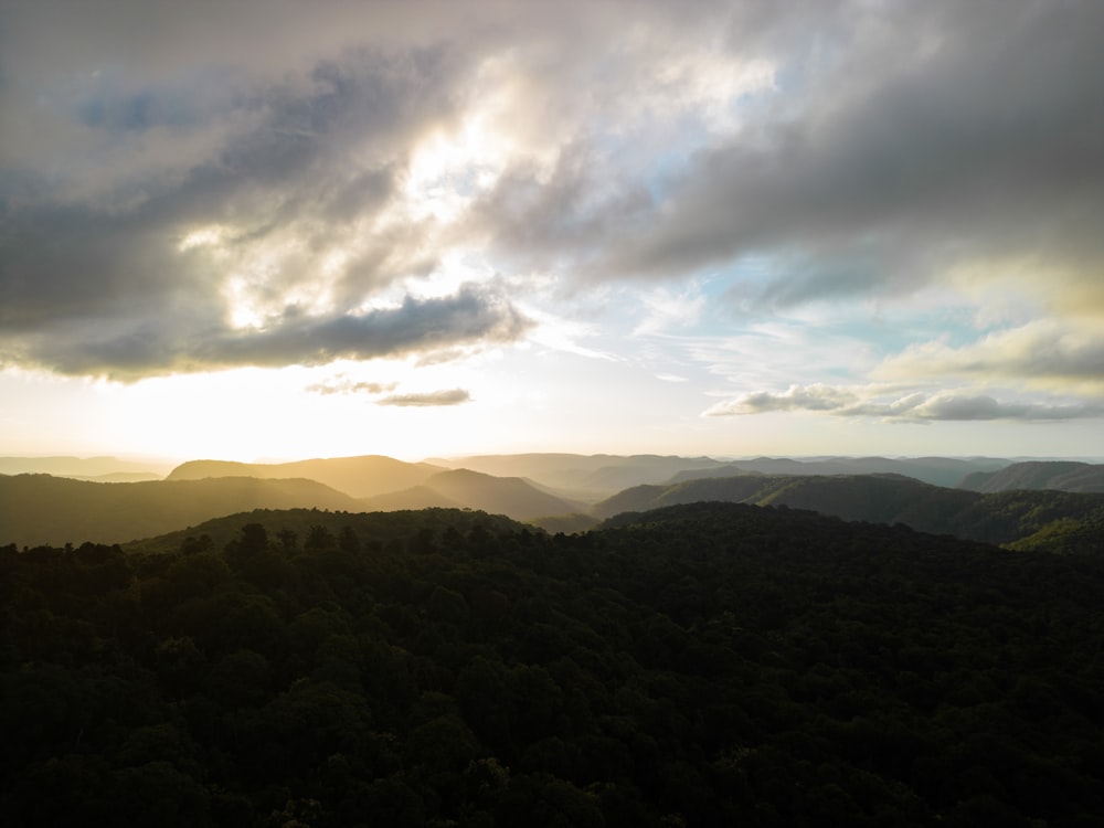 the sun shines through the clouds over the mountains