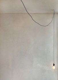 a room with a white wall and a black string hanging from the ceiling