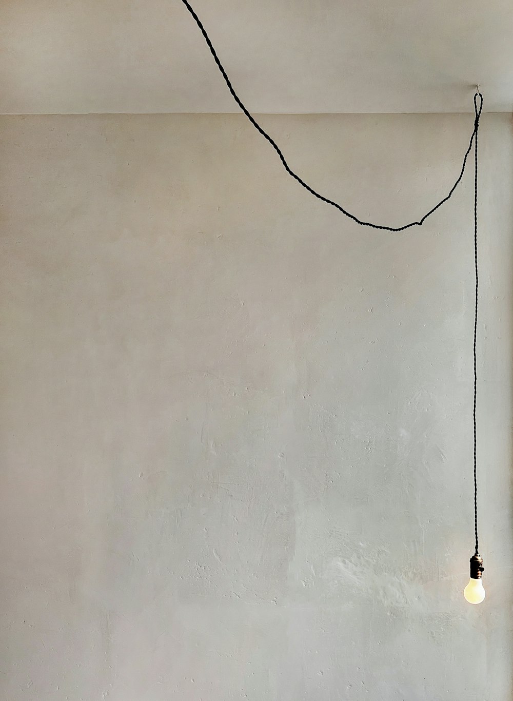 a room with a white wall and a black string hanging from the ceiling