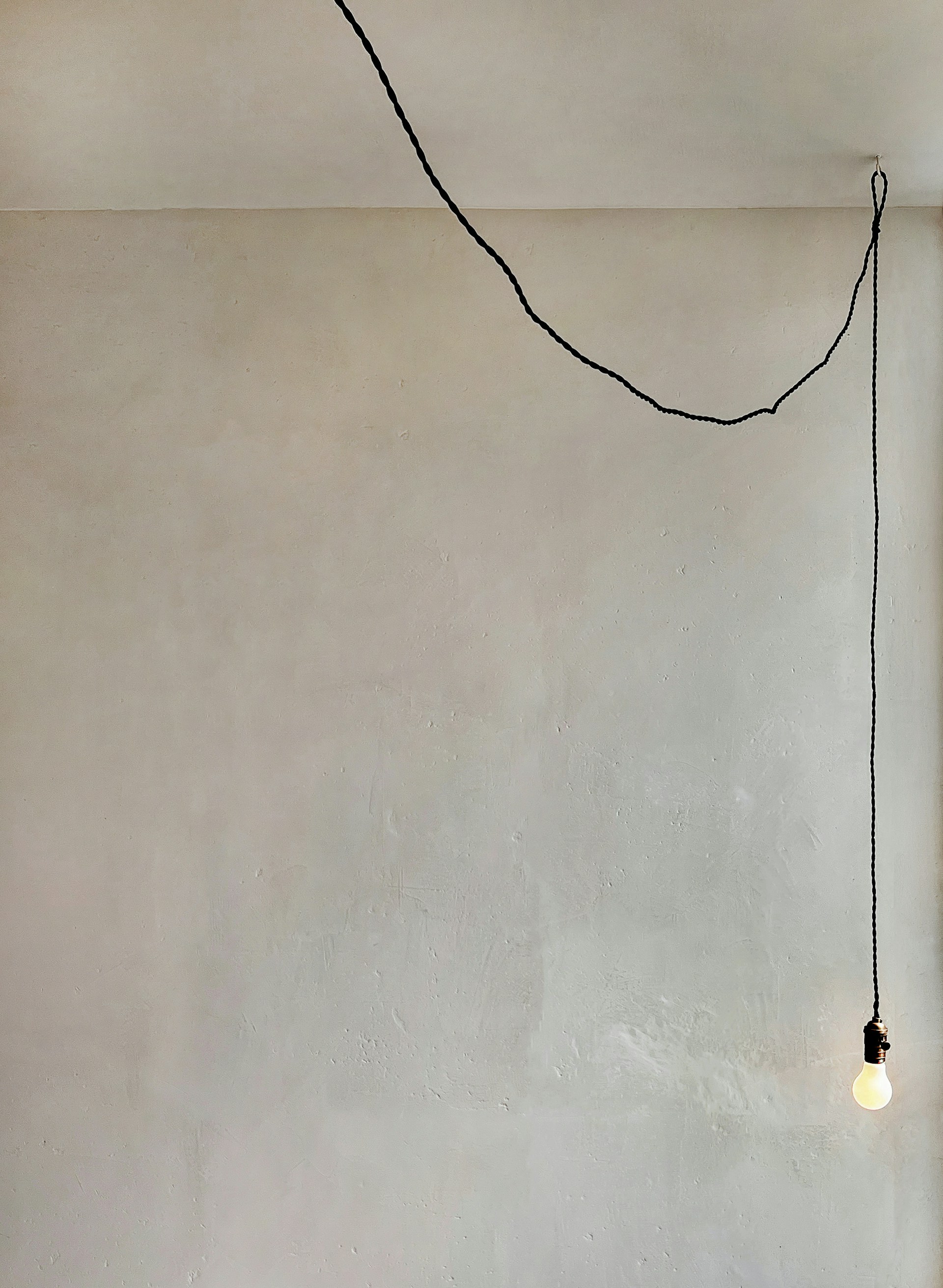 a room with a white wall and a black string hanging from the ceiling