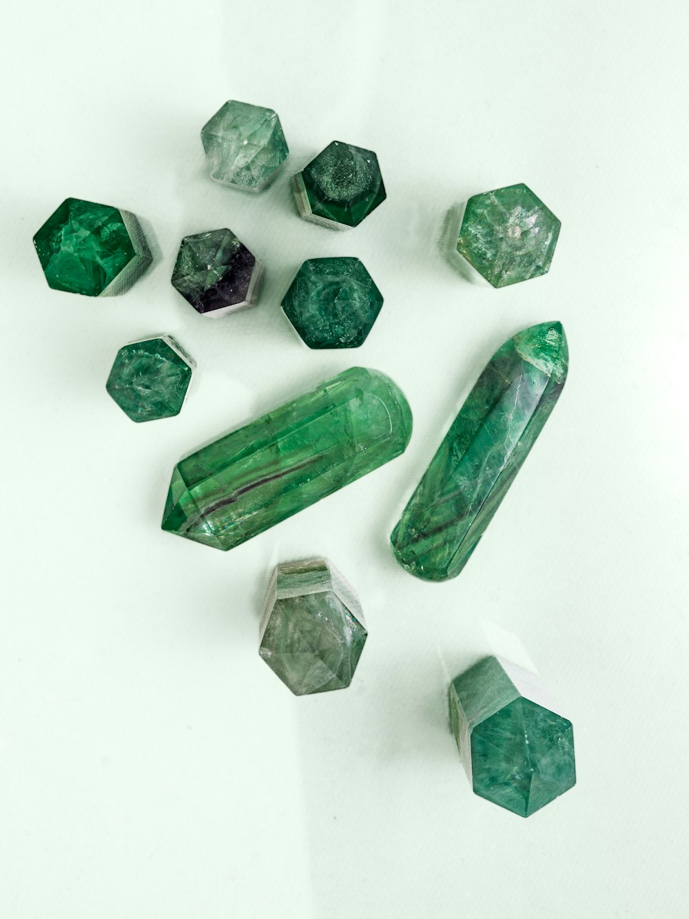un groupe de cristaux verts assis sur une table blanche