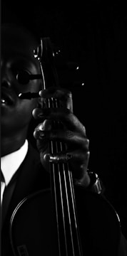 Portrait of the musician in a black suit with golden accents, holding a cello