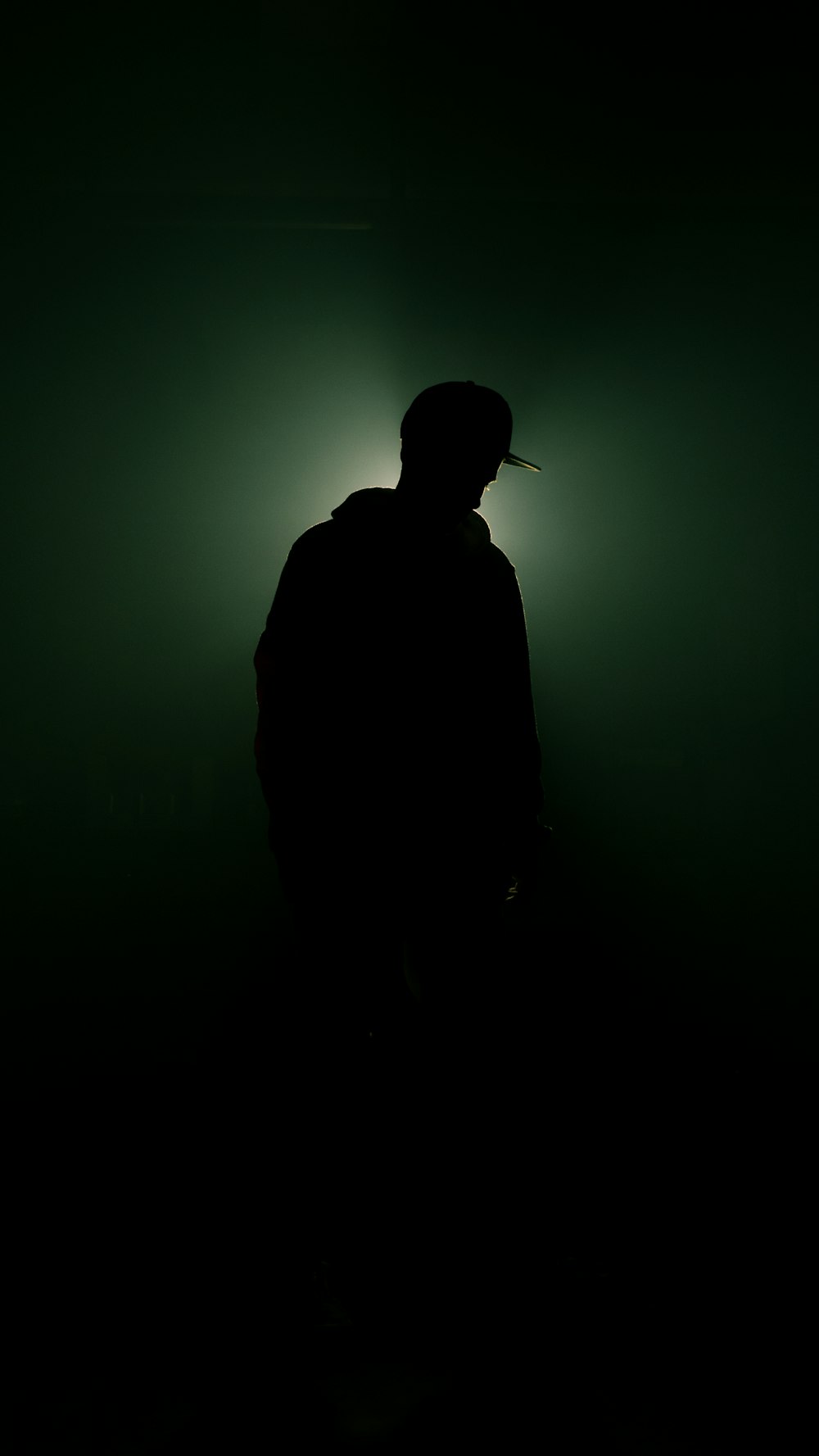 a man standing in the dark with a hat on