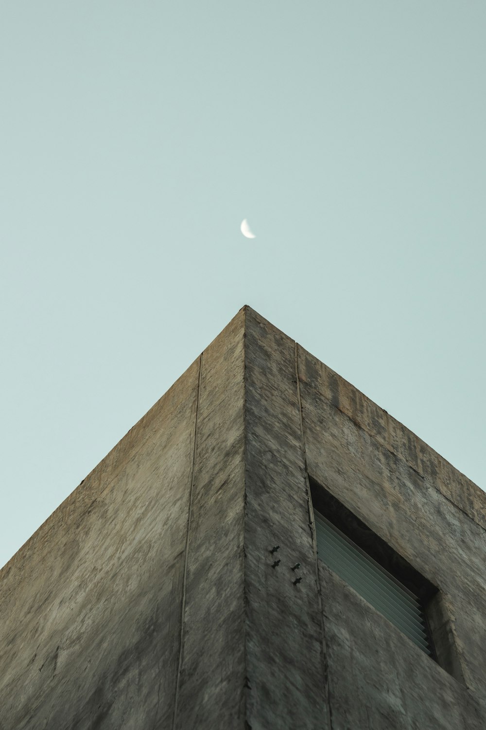 a tall building with a half moon in the sky