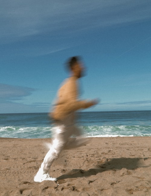 A runner moving across a sandy beach beside the ocean