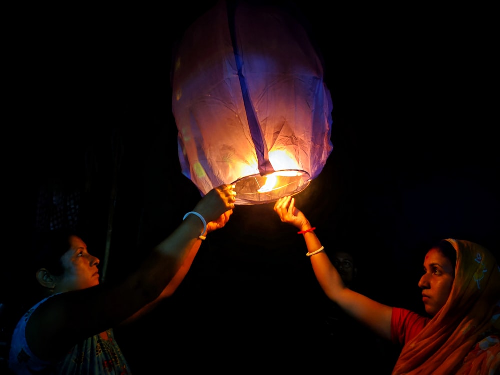 two women holding a lit up lantern in the dark