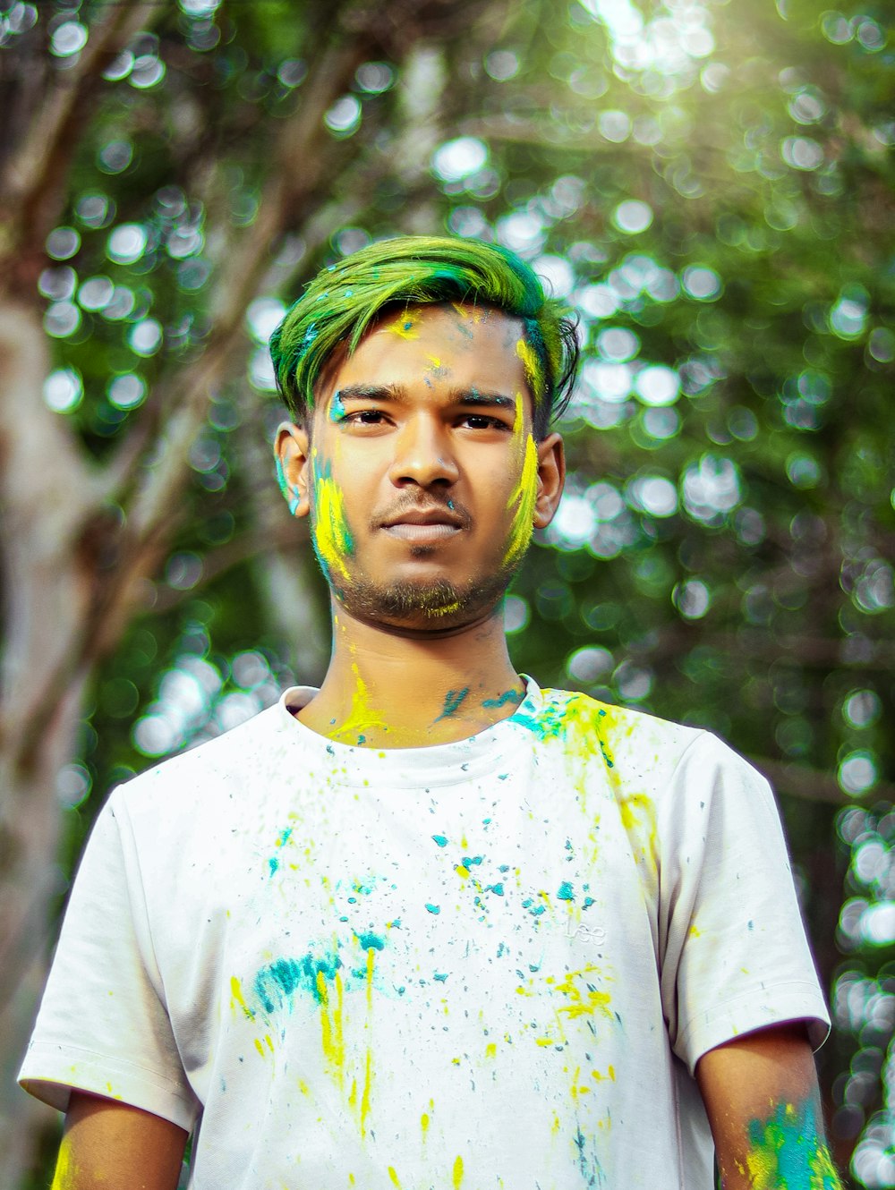 a man with green hair standing in front of a tree