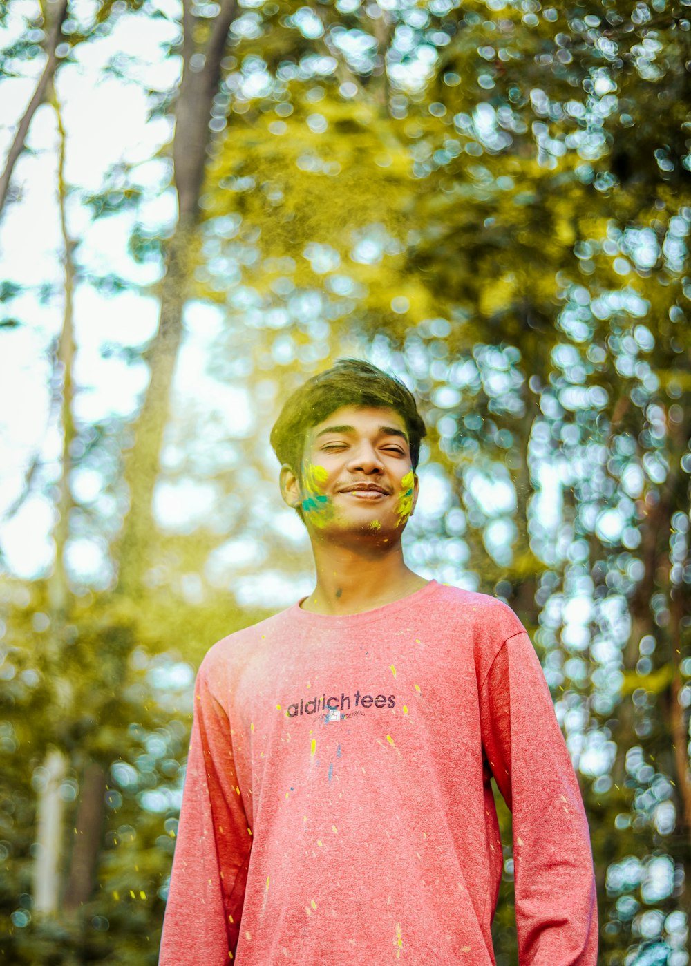 a young man standing in front of a forest