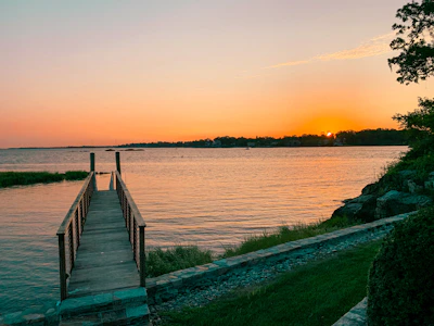 Charming lakeside cottage with a wooden dock and sunset view over the water.