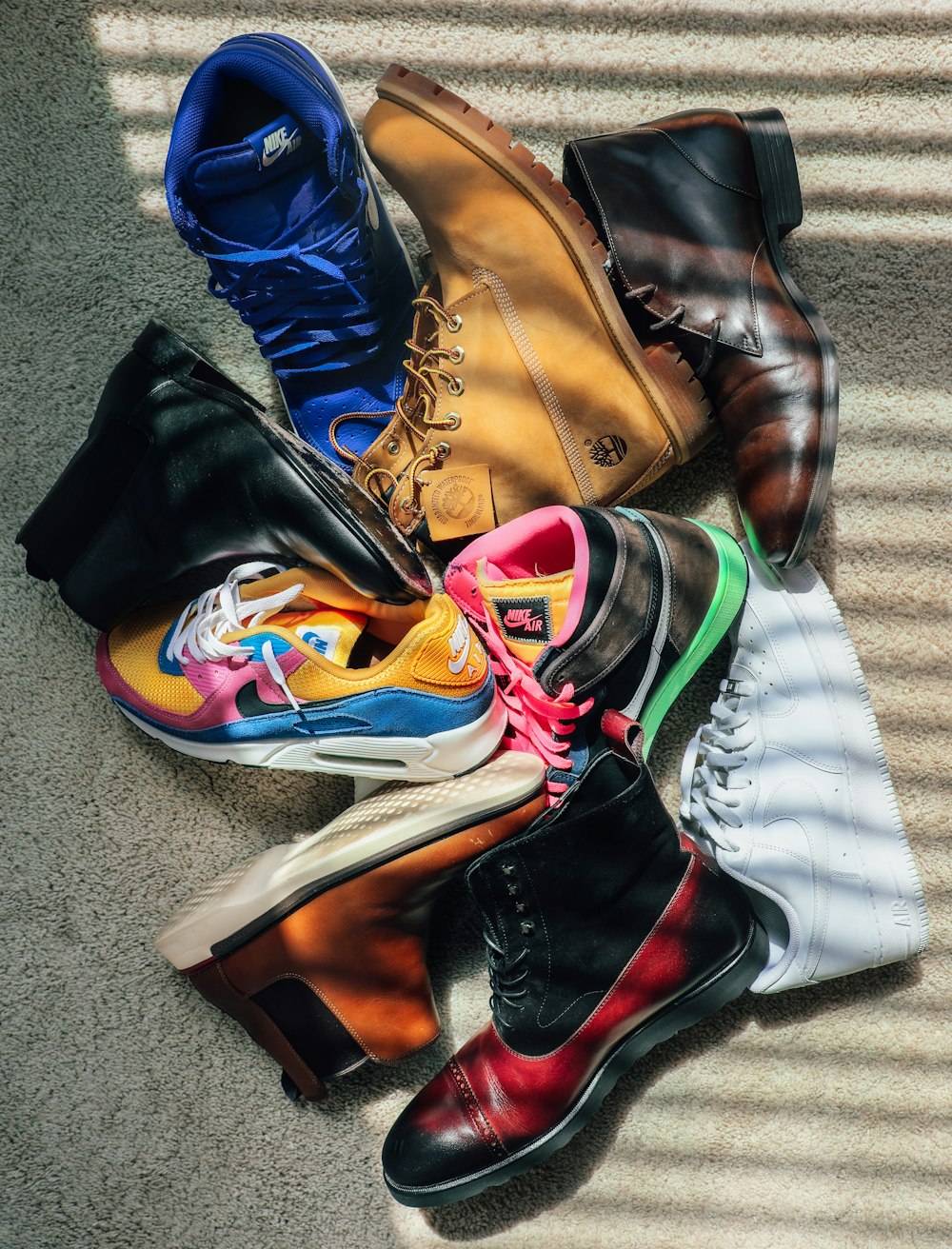 a pile of different colored shoes sitting on top of a carpet