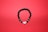 A round bracelet made of black beads arranged on a red background. Some beads are interspersed with metallic, decorative rings, and the bracelet features a yin-yang symbol as part of its closure.