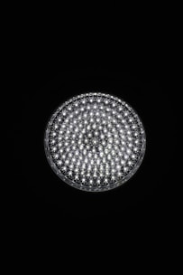 A circular light source composed of multiple small, bright LED bulbs, arranged densely in a grid pattern against a black background. The LEDs emit a cool white glow, creating a striking contrast.