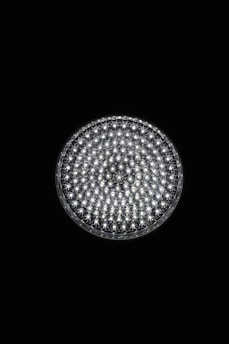A circular light source composed of multiple small, bright LED bulbs, arranged densely in a grid pattern against a black background. The LEDs emit a cool white glow, creating a striking contrast.