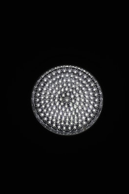 A circular light source composed of multiple small, bright LED bulbs, arranged densely in a grid pattern against a black background. The LEDs emit a cool white glow, creating a striking contrast.