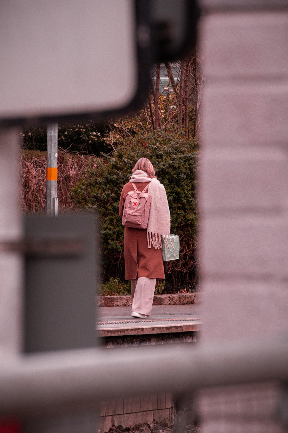 a woman in a pink coat is walking down the street