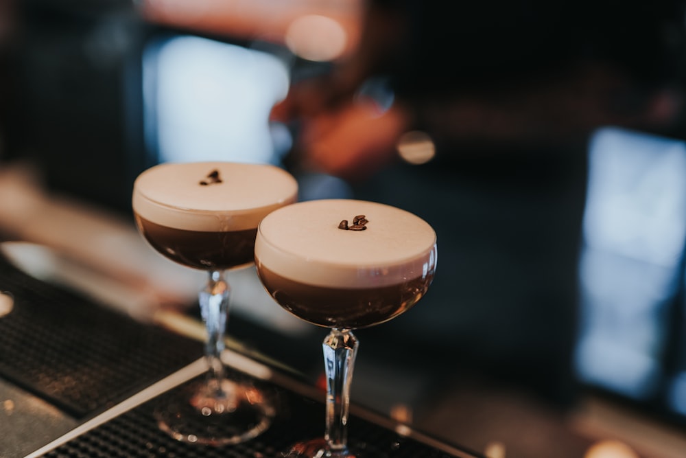 two glasses of chocolate drink sitting on a bar