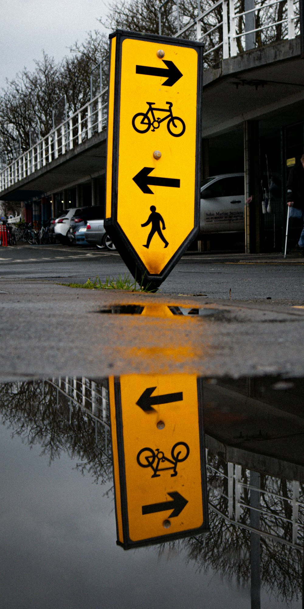 a yellow street sign with a reflection of a person on it