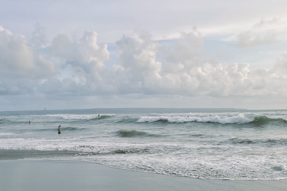 um grupo de pessoas em pé no topo de uma praia ao lado do oceano