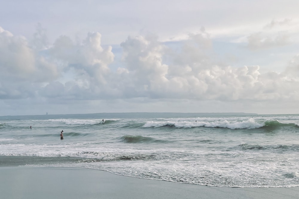 a group of people standing on top of a beach next to the ocean