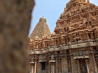 An intricately carved stone temple with detailed sculptures and architectural elements, showcasing traditional ancient design. The structure features large towers adorned with figures and motifs that depict historical or mythological scenes.