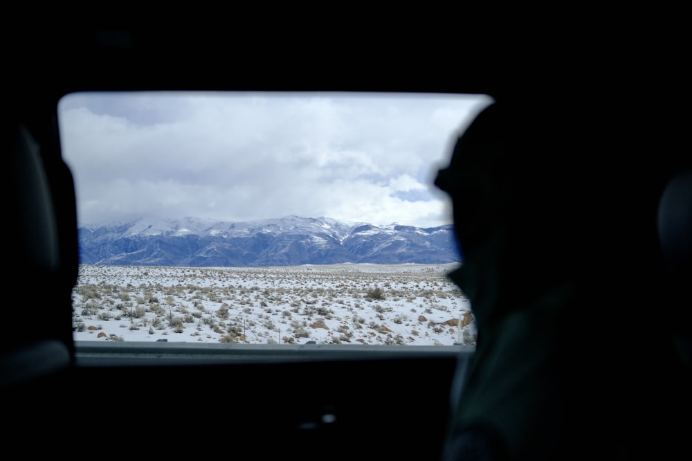 a view of a snowy mountain range from inside a vehicle