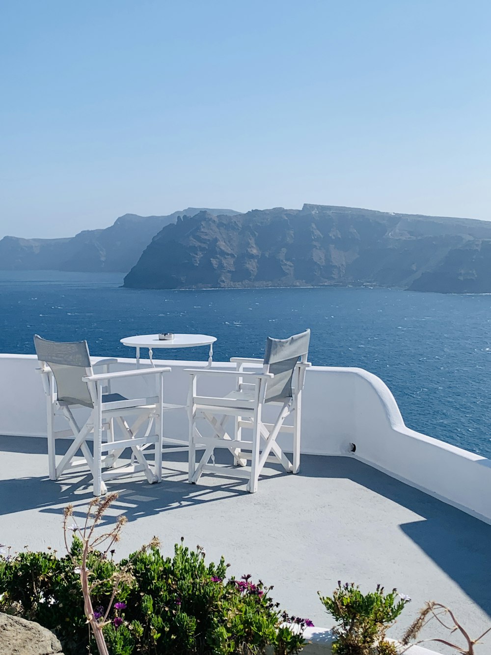 a table and chairs on a balcony overlooking the ocean