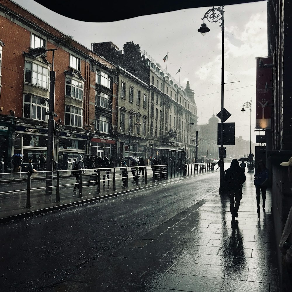 Gente caminando por una calle húmeda de la ciudad bajo la lluvia