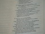 A close-up view of a page from a Bible, featuring passages in both regular and bold text. The text is formatted in a column with numbers preceding certain lines, set against a background of light-colored paper.