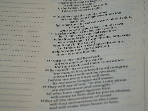 A close-up view of a page from a Bible, featuring passages in both regular and bold text. The text is formatted in a column with numbers preceding certain lines, set against a background of light-colored paper.