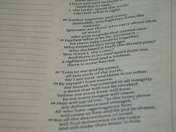 A close-up view of a page from a Bible, featuring passages in both regular and bold text. The text is formatted in a column with numbers preceding certain lines, set against a background of light-colored paper.