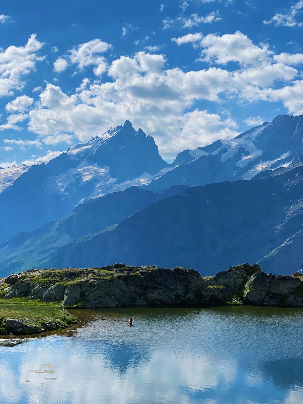 a lake surrounded by mountains under a blue sky