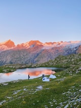 a couple of people standing on top of a lush green hillside