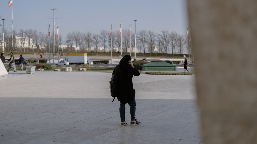 a person in a black jacket is standing in a plaza