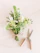 Close-up of a rustic bouquet featuring wildflowers and greenery tied with natural twine on a wooden table.