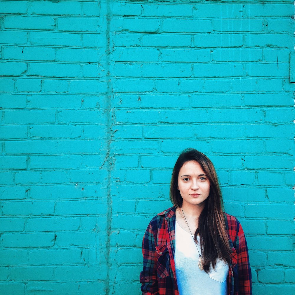 a woman standing in front of a blue brick wall