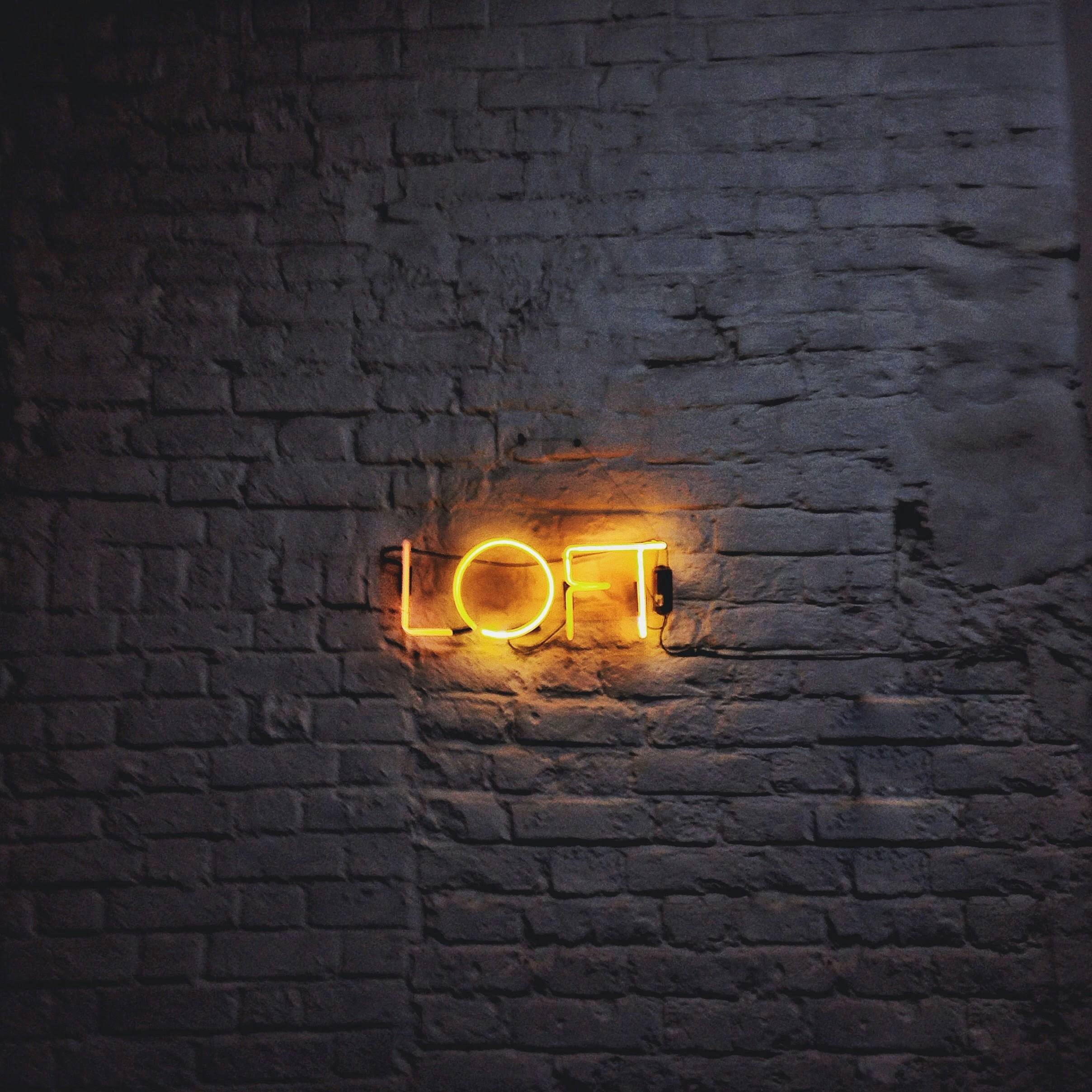 a brick wall with a neon sign on it