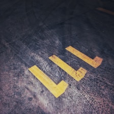 Close-up of a worker applying yellow paint to a parking space line.