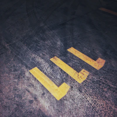 Close-up of a professional painter applying bright yellow safety lines on a dark asphalt parking lot.