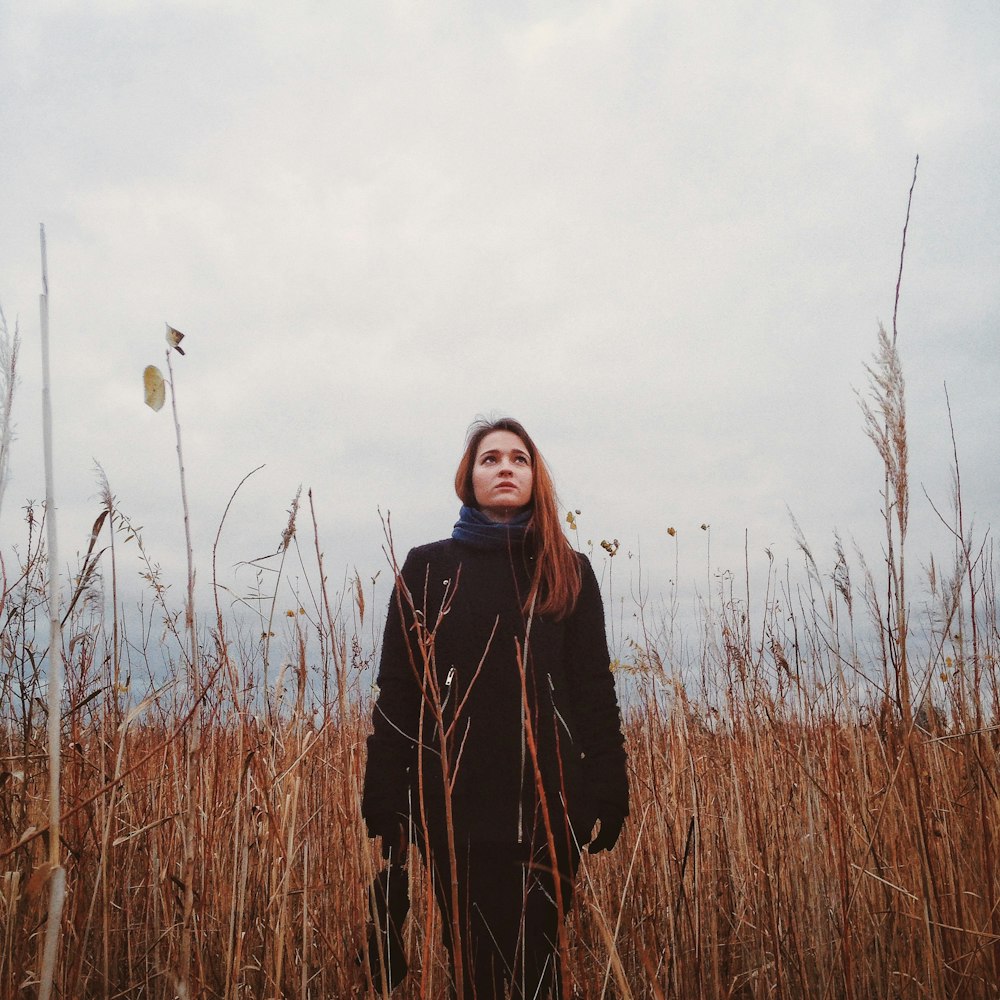 a woman standing in a field of tall grass