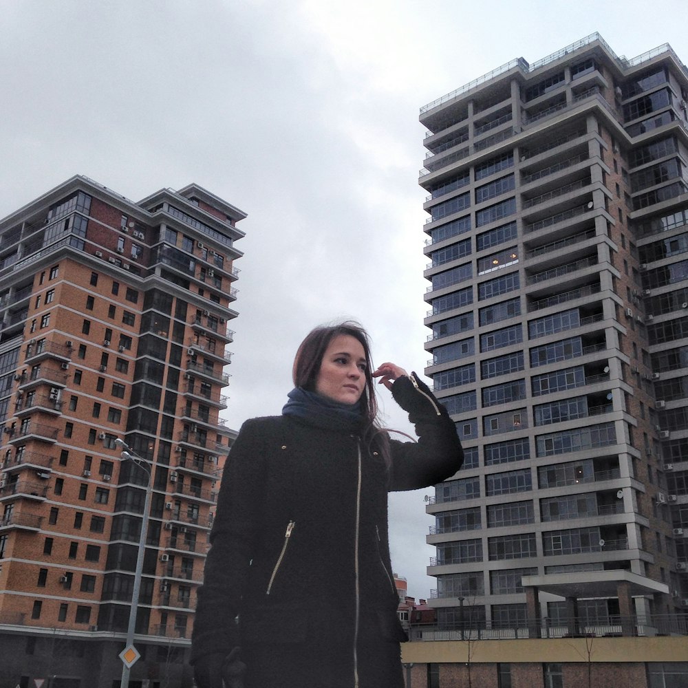 a woman standing in front of two tall buildings