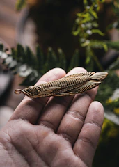 Hands gently holding a golden charm surrounded by fresh flowers and spiritual symbols.