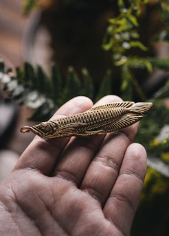 Hands gently holding a golden charm surrounded by fresh flowers and spiritual symbols.