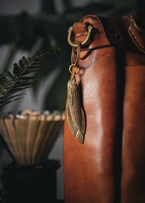 A stylish brown mug with a matching key chain and beige bag in the background.
