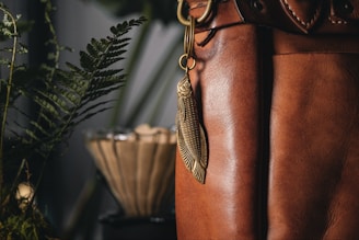 Close-up of a minimalist leather keychain hanging from a rustic wooden hook.