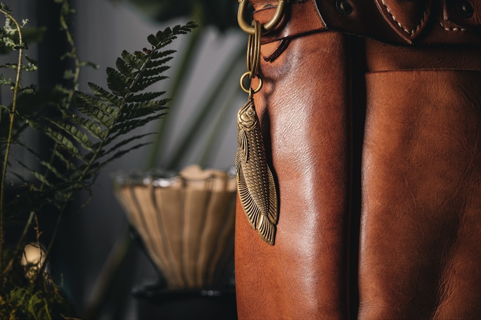 Close-up of a minimalist leather keychain hanging from a rustic wooden hook.