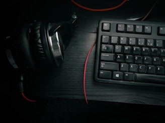 Minimalist studio setup with headphones resting on a keyboard, bathed in soft grayscale lighting.