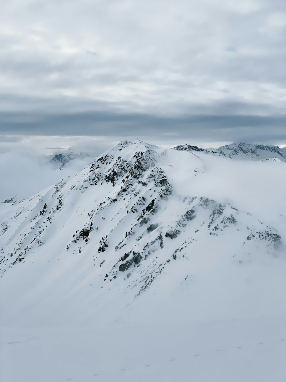 a mountain covered in snow under a cloudy sky