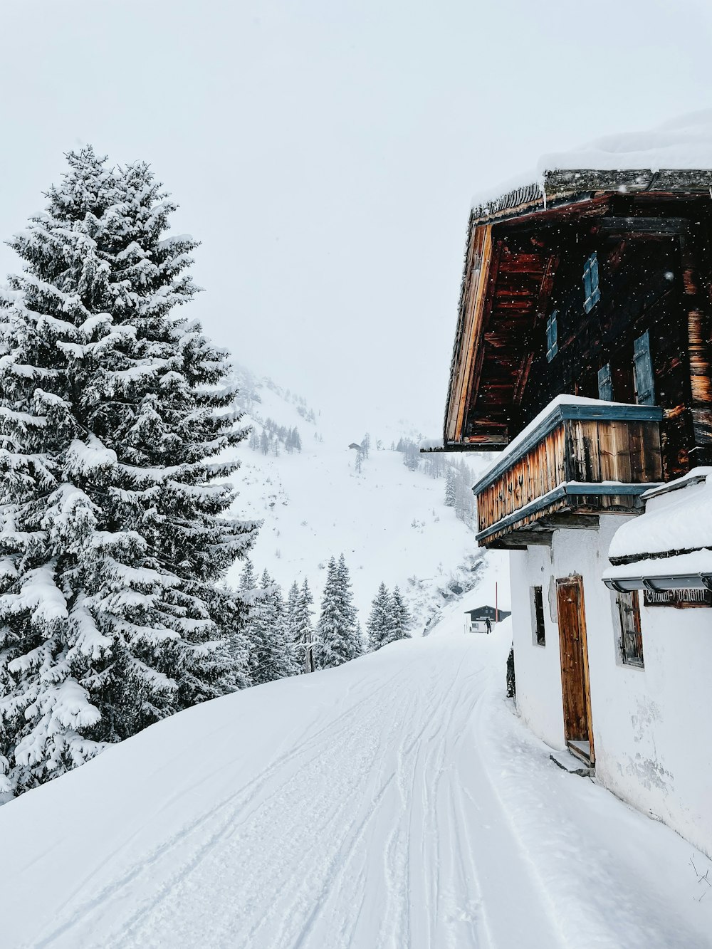 a snow covered ski slope with a building and trees